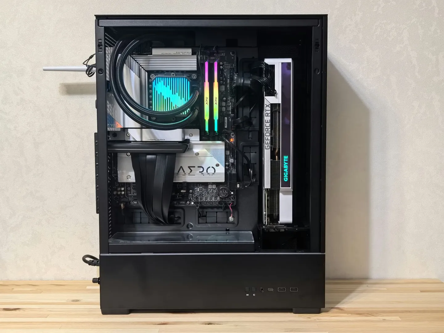 Desktop computer with its side panel removed, showing a graphics card, liquid cooling tubes, and illuminated memory
