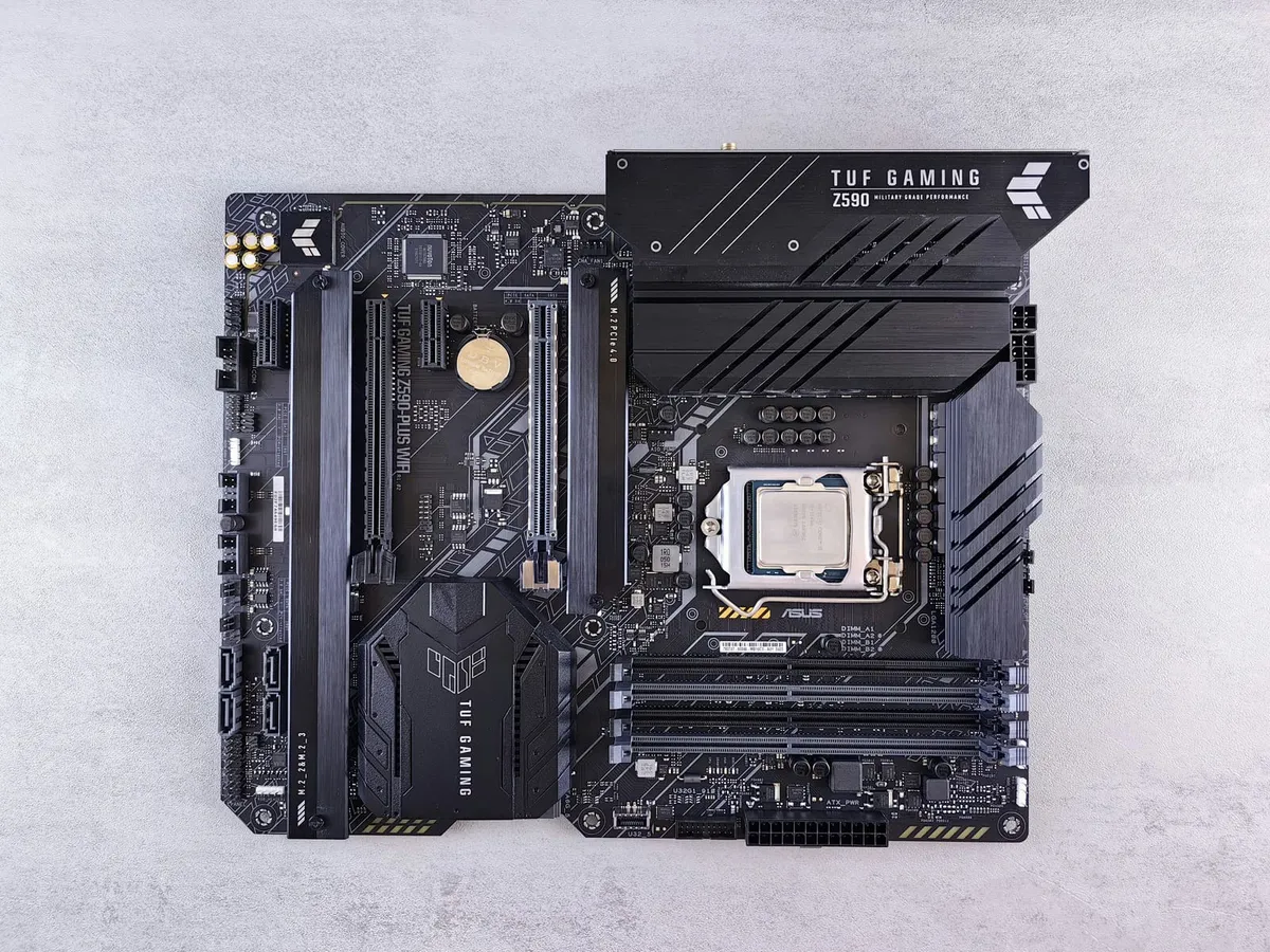 Black desktop motherboard with a processor installed and empty memory slots
